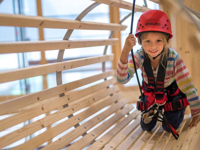 Ein Kind klettert gesichert durch ein Hinderniss im hauseigenen Kletterpark des Familenhotels Feldberger Hof